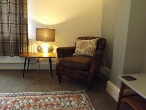uma sala de estar com uma cadeira e uma mesa com um candeeiro em Wells Cottage em Malvern Wells
