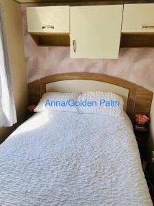 a bedroom with a white bed with a wooden headboard at Golden Palm, 8 Berth Caravan in Skegness