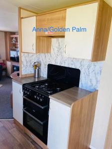 a kitchen with a black stove and white cabinets at Golden Palm, 8 Berth Caravan in Skegness