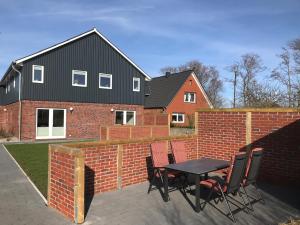 ニービュルにあるUrlaubswindのレンガの壁の前にテーブルと椅子付きのパティオ +28枚の写真