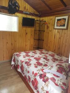 um quarto com uma cama com colcha floral em Cabana Hostel nas Árvores EcoPark em São Pedro