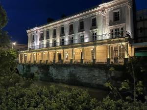 a large white building at night with a river at Victoria Colonnade Aparthotel in Leamington Spa
