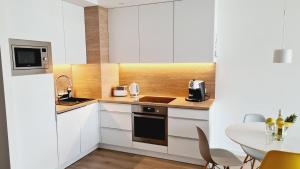 a kitchen with white cabinets and a table at Apartament Klifowa Rewal 16 in Rewal