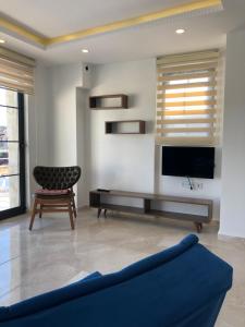 a living room with a blue couch and a tv at Stone House Aparts 2 plus 1 mit zwei Balkone und Poolview Kalkan No 10 in Kas