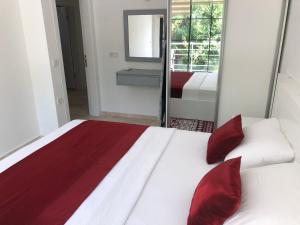 a bedroom with a bed with red pillows and a mirror at Stone House Aparts 2 plus 1 mit zwei Balkone und Poolview Kalkan No 10 in Kas +21 photos