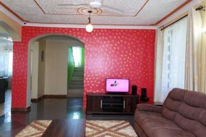 SERENE 4 BEDROOMED HOME IDEAL FOR FAMILY HOLIDAY في مومباسا: غرفة معيشة مع تلفزيون على جدار احمر