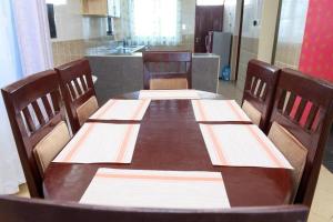 a wooden table with four chairs and a kitchen at SERENE 4 BEDROOMED HOME IDEAL FOR FAMILY HOLIDAY in Mombasa