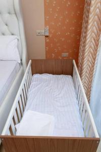 モンバサにあるSERENE 4 BEDROOMED HOME IDEAL FOR FAMILY HOLIDAYのベッド2台付きの客室で、小さなベビーベッド1台を利用できます。