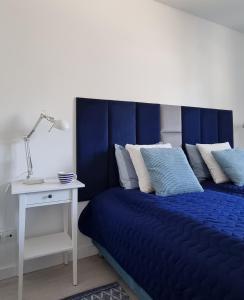 Schlafzimmer mit einem blauen Bett und einem weißen Tisch in der Unterkunft Apartament Azzurro in Międzywodzie