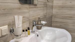 La salle de bains est pourvue d'un lavabo blanc et d'un miroir. dans l'établissement Harmonia Garden Hotel&Restaurant, à Garni