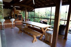 drewniany stół i ławka w pokoju z oknami w obiekcie Chalé com lazer no Hotel Fazenda China Park ES w mieście Domingos Martins