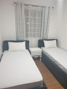 a bedroom with two beds and a window at Lovely 2 and 1 bedroom guest units Karen in Nairobi