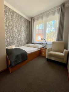 a bedroom with a bed and a chair and a window at Gościniec Rospuda in Augustów