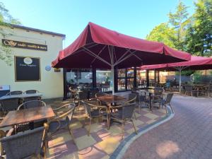 um restaurante com mesas e cadeiras e um guarda-sol vermelho em Hotel Diana em Schönwalde