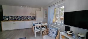 eine Küche und ein Wohnzimmer mit einem TV und einem Tisch in der Unterkunft Apartament Azzurro in Międzywodzie