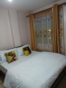 a bedroom with a large white bed with yellow pillows at JJ homes 3 bedroom @Regal point apartments in Nairobi