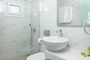 a white bathroom with a sink and a shower at Faros View in Kinira