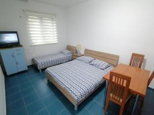 um quarto com duas camas e uma mesa e uma televisão em Vila Mila em Budva