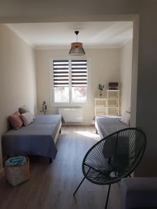 1 dormitorio con 2 camas, silla y ventana en EOLE - Maison Saint Jean de Monts - 2 pièces - 4 personnes en Saint-Jean-de-Monts
