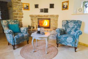 a living room with two chairs and a table and a fireplace at Babér Cottage Vendégház Tihany in Tihany