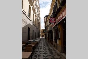 eine Gasse mit Tischen und Gebäuden in einer Stadt in der Unterkunft Apartamento Centro Ciudad Ronda in Ronda