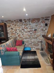 a living room with a couch and a stone wall at Caramulo - Abrigo Serrano in Carvalhal da Mulher