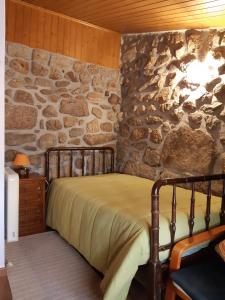 a bed in a room with a stone wall at Caramulo - Abrigo Serrano in Carvalhal da Mulher
