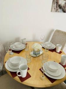 una mesa de madera con platos blancos y tazas. en Blessed Roker home with free parking., en Monkwearmouth