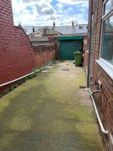 an alley between two brick buildings with a green garage at Blessed Roker home with free parking. in Monkwearmouth