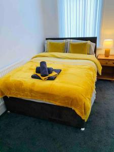 a bed with a yellow blanket and two towels on it at Blessed Roker home with free parking. in Monkwearmouth