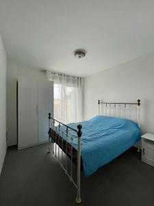 sypialnia z łóżkiem z niebieską narzutą i oknem w obiekcie Apartment, La Tejita. w mieście La Tejita