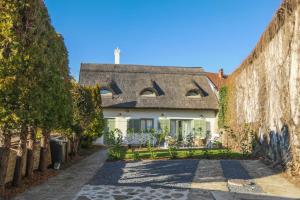 an old house with a thatched roof and a stone road at Babér Cottage Vendégház Tihany in Tihany