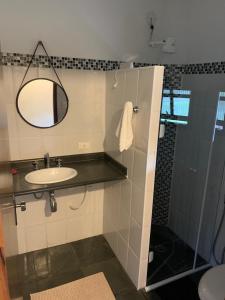 La salle de bains est pourvue d'un lavabo et d'une douche avec un miroir. dans l'établissement Chales em Salesopolis - Recanto da Barra, à Salesópolis