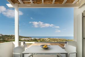 a table and chairs on a balcony with a view of the ocean at NiMa Sifnos Residences in Apollonia