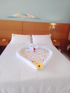 Una cama blanca con una bandeja en forma de corazón. en Pousada Lua Azul, en Porto de Galinhas