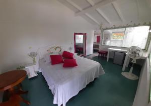 1 dormitorio con cama blanca y almohadas rojas en HOTEL CAMPESTRE - BRUGMANSIA - Fincahotel, en Montenegro