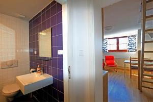 a bathroom with a sink and a red chair at Apartmány Fox in Boží Dar
