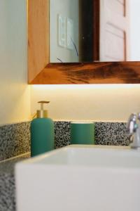 a bathroom sink with a mirror and a soap dispenser at Pousada Casa de Hóspedes in Icaraí