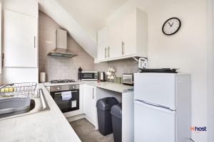 a kitchen with white appliances and a clock on the wall at Host Liverpool - Family Home Near Centre, Pets OK & Free Parking in Liverpool