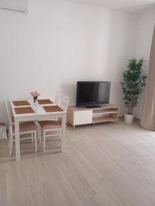 sala de estar con TV y mesa con sillas en APARTAMENTO LUPA, en Cádiz