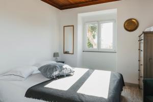 a white bedroom with a bed and a window at Bird House in Lourinhã