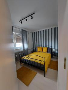 a bedroom with a yellow bed with striped walls at Center Firefly Danube Apartment in Novi Sad