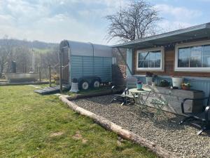 una caravana estacionada en un patio al lado de una casa en Belan Bluebell Woods Shepherds Hut en Llanidloes