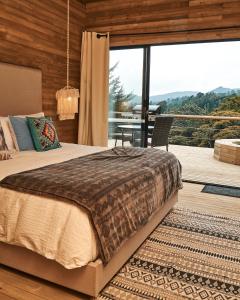 1 dormitorio con 1 cama y balcón con mesa en Bleu Hills Glamping Llanogrande, en Rionegro