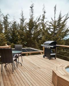 - un barbecue sur une terrasse en bois avec une table et des chaises dans l'établissement Bleu Hills Glamping Llanogrande, à Rionegro