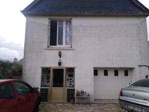 a white house with a red car parked in front of it at Aux portes de locronan in Quéménéven