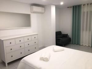 a bedroom with a bed and a dresser and a chair at Bmar in Quarteira