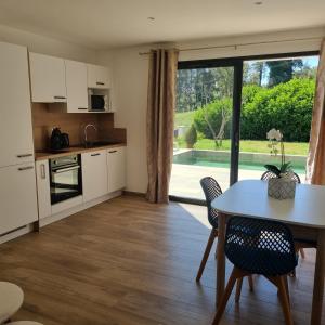 a kitchen and dining room with a table and chairs at Rez de villa avec piscine privée, wifi, jardin clôturé in Penta-di-Casinca