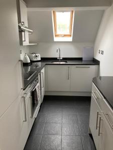 Una cocina con gabinetes blancos y un fregadero y una ventana. en Letting Serviced Apartments - Chorleywood Village, en Chorleywood