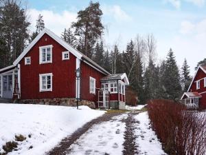 una casa roja en la nieve con entrada en Holiday home ÅTVIDABERG V en Sturefors